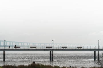 Riverbank walkway  with benches facing the river and bridge