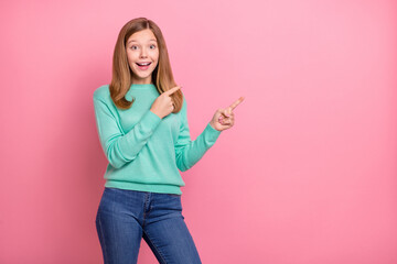 Photo of excited funky school girl dressed teal pullover pointing empty space isolated pink color background