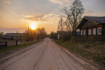 Car riding on a country dirt gravel road with on a spring sunset. Russian village