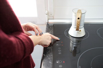 Anonymous girl turning on the ceramic hob