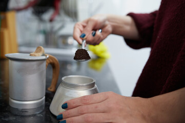Side view of an anonymous girl putting coffee in a coffee pot