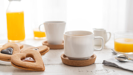 Fototapeta na wymiar Breakfast concept with coffee, orange juice and cookies in heart shape with jam