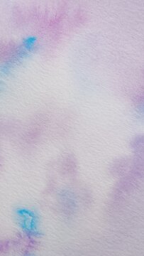 Background with abstract ink stains made with watercolor in blue, purple and pink colors on textured paper