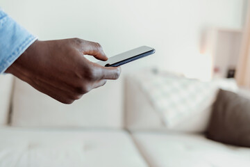 Cropped shot of a handsome young man using his cellphone while chilling on the sofa at home. Mobile communication concept.