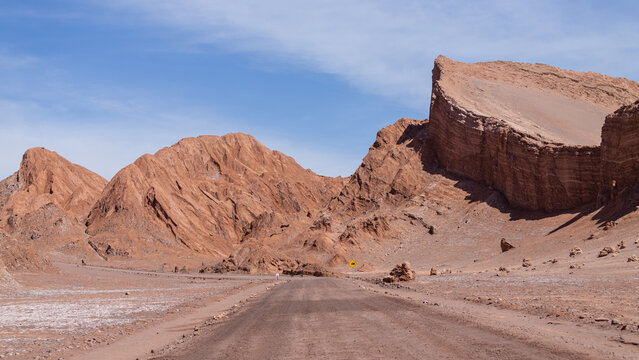 Stra&szlig;e f&uuml;hrt durch die roten Berg- und Lehmformationen der W&uuml;stenlandschaft des Valle de la Luna, des Mondtals, in den Weiten der Atacama W&uuml;ste im Norden Chiles