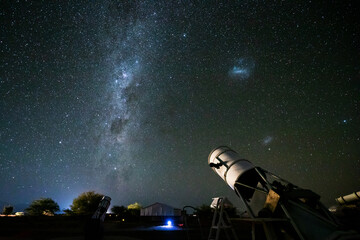 Ein Teleskop steht in mitten der Atacama Wüste vor den unzähligen Sternen der Milchstraße.