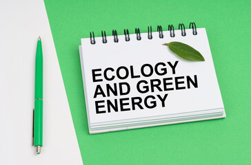 On a white-green background lies a pen, a leaf of a plant and a notepad with the inscription - Ecology And Green Energy