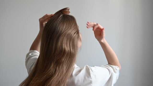a girl with problematic hair sits on the bed and combs them. girl with a comb sits on a bed in pajamas