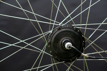 Repair of electric bicycles. Bicycle wheel, spokes and electric motor close-up on a black background.
