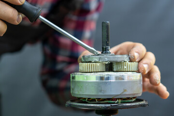 Repair of a bicycle electric motor. The disassembled motor is installed in a vise for maintenance, grease replacement, gear cleaning.