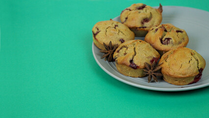 five muffins made of rice flour, yogurt, cherries and pumpkin oil lie on a white plate on a green background, side view. gluten-free homemade cakes. copy space