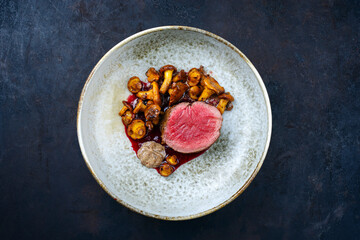 Modern style traditional barbecue dry aged angus beef tenderloin steak natural with chanterelle mousse parfait and wild cherry relish cream served as top view in a Nordic design plate with copy space