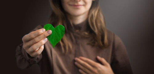 Woman on redshirt hands holding heart-shaped leaves CSR , ESG, Eco green sustainable living, environmental, social and corporate governance. Environmental and Ecology Care Concept.