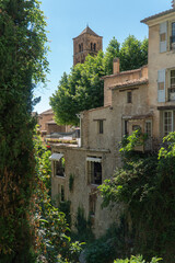 Fototapeta na wymiar Moustiers-Sainte-Marie, Provence-Alpes-Côte d'Azur - France - July 13 2021: Church of Moustiers-Sainte-Marie hidden by residential houses and surrounded by trees.