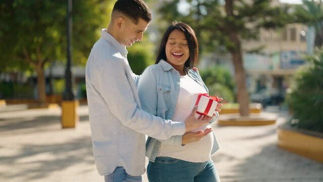 Young latin couple smiling confident suprise with gift at park