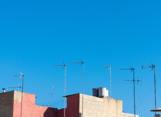 antenas de radio y televisión en azoteas con cielo de fondo azul.