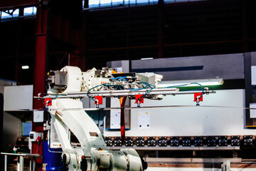 Robotic arm working with metal sheet at hydraulic bending machine