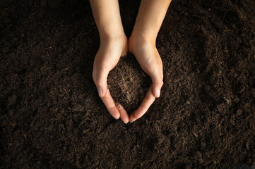 Dirty woman hands holding dark moist soil. Agriculture, organic gardening, planting or ecology concept. Environmental, earth day. Banner. Top view. Copy space. Farmer checking before sowing.