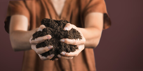 Dirty woman hands holding dark moist soil. Agriculture, organic gardening, planting or ecology concept. Environmental, earth day. Banner. Top view. Copy space. Farmer checking before sowing.
