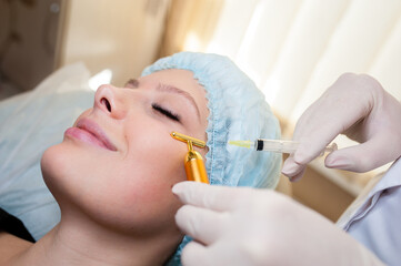 Beautiful woman getting lifting injection in cheekbones. Injections of skin rejuvenation. Cosmetic procedures, injections.