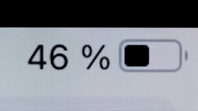 Timelapse - smartphone, tablet battery level indicator running low - from 100 to zero percent: close up macro top view of gadget display, screen. Energy, power, digital and time lapse concept