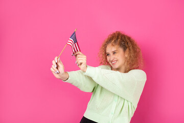 A young happy girl with a smile on her face holds an American flag in her hands. Symbol of patriotism and freedom.