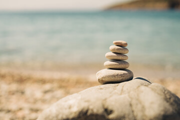 Pyramid stones balance on the sand of the beach. Zen balance, minimalism, harmony and peace. Selective focus