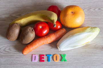 Grapefruit, banana, kiwis, carrot, endive and tomatoes with the word detox