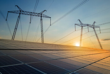 High voltage towers with electric power lines transfering energy from solar photovoltaic panels at...