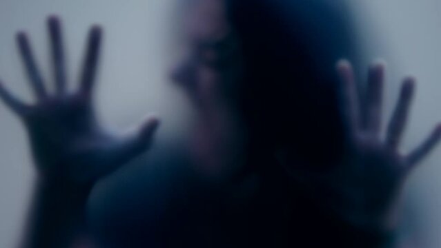 Defocused shot of Scary woman in despair behind glass emotional pain concept