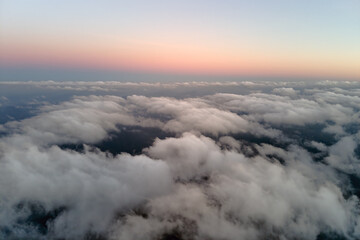 Aerial view from above at high altitude of dense puffy cumulus clouds flying in evening. Amazing...