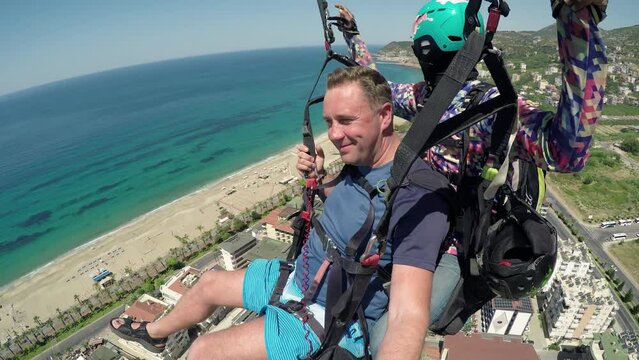 Paragliding without a motor. Flying on a tandem paraglider with an instructor pilot over the city and sea coast