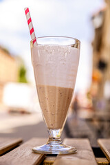 Mocha iced coffee with a cocktail tube on a wooden table in a cafe.