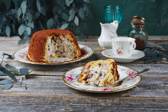 Traditional Italian Panettone cake stuffed with ricotta pudding, glanced fruits and raisins served as close-up on a classic design plate