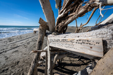 une construction de bois sur une plage avec un texte sur la beauté gravé sur une planche