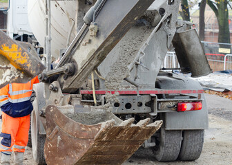 Exavator bucket filled with wet concrete to bring it to plce of concrete works on building site