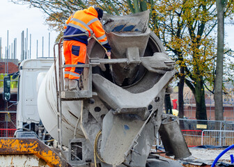 Delivery driver washing concrete vagon after delivering concrete on building site