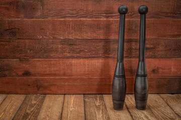 pair of Indian clubs (solid cast polyurethane with a steel core) against rustic, weathered wood...
