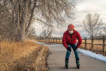 senior male is inline skating on a paved bike trail along Poudre River in Colorado, fall or winter...