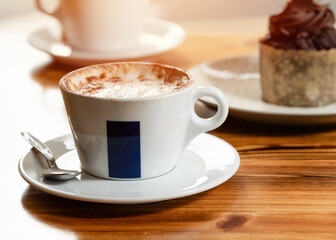 cup of coffee with cake on wooden table in cafe