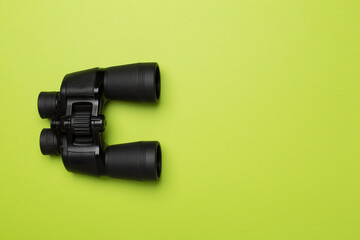 Black binoculars on color background. Top view