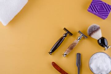 Different old vintage razors, foam, towels, and brush on a   yellow  background. View from above Space for text