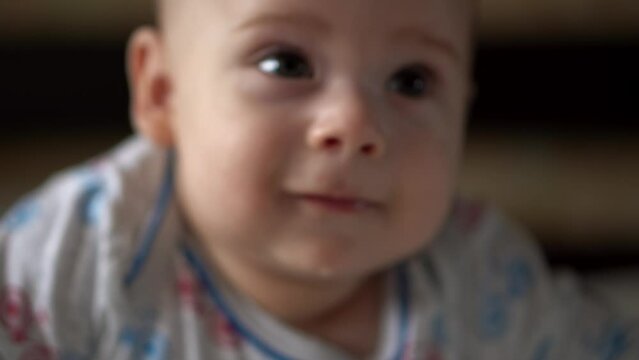 Newborn Active Baby Cute Smiling Teethless Face Portrait Early Days On Stomach Developing Neck Control. 5 Months Child On White Bed Looking on Camera. Infant, Childbirth, Parenthood, Beginning Concept