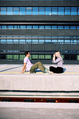 A happy teenage couple is sitting at the train station and taking photos.