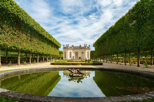 Versailles, France - August 02 2020: The French Pavilion and French Garden at the Petit Trianon in Versailles with a pond in the foreground.