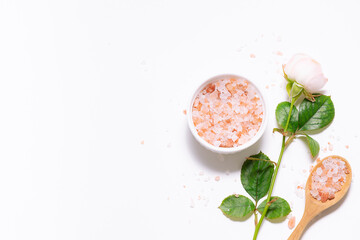 Creative composition with pin Himalaya salt and aromatic rose flower on white background top view. Spa and wellness concept, copy space for your design.