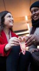 women looking at each other focusing on a candy heart