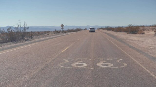 Route 66 road sign. Historic street with nobody. Classic concept for travel and adventure in a vintage way. Street sign on historic route 66 in the Mojave desert photographed against the sun at sunset