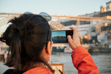 A beautiful shot of a Spanish girl taking a photo of a cityscape in porto