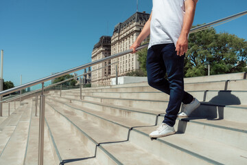 unrecognizable latino man with a jean and white sneakers going down a cement stairs. Horizontal orientation.